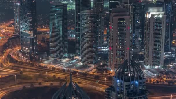 Rascacielos deportivos JLT y Dubai cerca de Sheikh Zayed Road timelapse noche aérea. Edificios residenciales — Vídeos de Stock