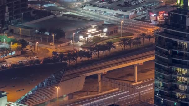 Futuristické budovy v Dubaji se stanicí metra a luxusními mrakodrapy za sebou poblíž Dubai Marina noční timelapse — Stock video