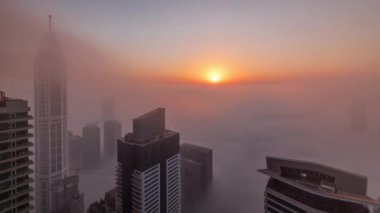 Dubai Marina silueti üzerinde nadir kış sisi ve güneşli hava saatleriyle aydınlatılan gökdelenler..