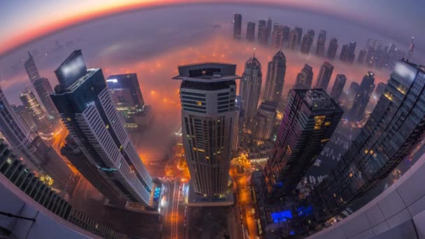 Rara niebla de invierno temprano en la mañana sobre el horizonte de Dubai Marina y rascacielos iluminados por luces de la calle noche aérea al día timelapse. — Vídeos de Stock