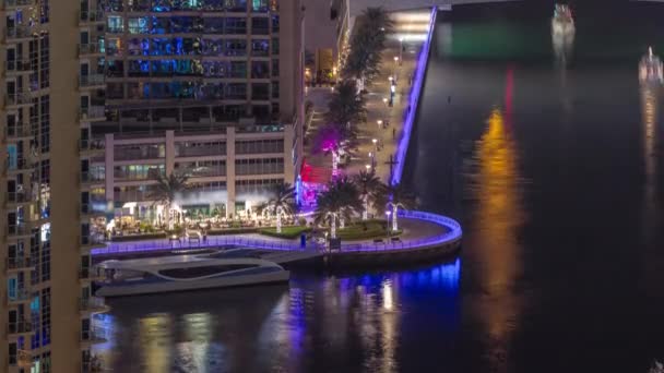 Променад и канал в Dubai Marina с роскошными небоскребами по ночному времени, Объединенные Арабские Эмираты — стоковое видео