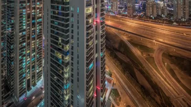 Flygfoto över Dubai marina och JLT skyskrapor med glödande fönster natt timelapse med trafik på shejk zayed väg. — Stockvideo