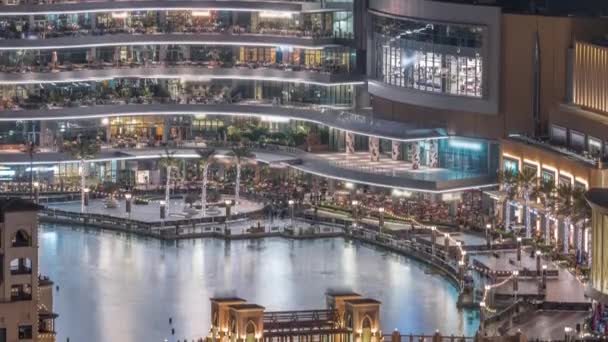 Centro comercial exterior con reataurantes cerca de la fuente en el centro de Dubái timelapse noche aérea, Emiratos Árabes Unidos — Vídeos de Stock