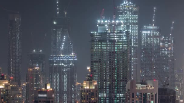 Edificios altos de varios pisos en construcción y grúas en horario nocturno — Vídeos de Stock
