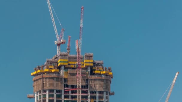 Edificio alto de varias plantas en construcción y timelapse de grúas — Vídeo de stock