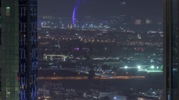 Widok na plac budowy, wille i słynny hotel w linii horyzontu z Dubai Water Canal antenowa noc timelapse — Wideo stockowe