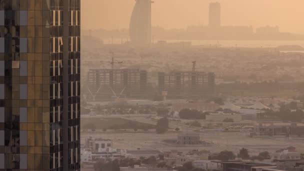 Utsikt över byggarbetsplatsen, villor och berömda hotell i horisonten linje från Dubai Water Canal under solnedgången antenn timelapse — Stockvideo