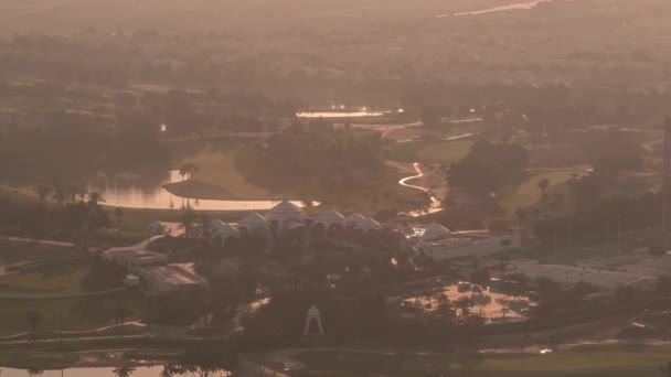 Vista aérea al campo de golf durante el amanecer y el sol reflejado desde el agua en los lagos timelapse. — Vídeos de Stock