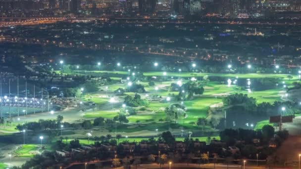 Letecký pohled na golfové hřiště se zeleným trávníkem a jezery, vilové domy za ním noc timelapse. — Stock video