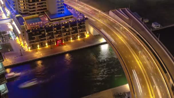 Dubai Marina di notte vista sul fiume con barche e ponte con timelapse traffico vicino all'hotel — Video Stock