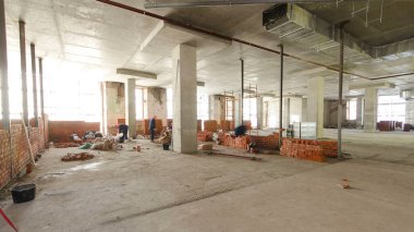 Panorama duvarları örmek için tuğla döşeyen duvarcıları gösteriyor. Profesyonel inşaat işçisi sanayi bölgesinde tuğla döşeyip bina inşa ediyor..