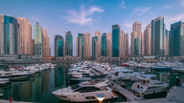 Dubai Marina, açık bir sabahta, mavi gökyüzü boyunca, gece gündüz, yat kulübünden gelen pek çok yatla, parlayan ışıklar ve en yüksek gökdelenlerle geçiş zamanı. Işıklar kapanıyor.