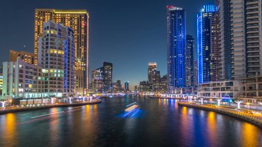 Dubai Marina rıhtımı, Dubai 'deki köprüden gece vardiyasına kadar uzanan kuleleri ve yatları olan Birleşik Arap Emirlikleri. Gün batımından sonra yapay kanallı bölge