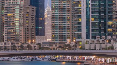 Dubai Limanı 'nın deniz manzarasını, köprüden geceye geçiş zamanı olan kuleler ve yatlarla kapatın. Birleşik Arap Emirlikleri. Yapay kanalları ve gökdelenleri olan bir bölge.