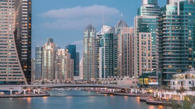 Dubai Marina rıhtımı, Dubai 'deki köprüden gece vardiyasına kadar uzanan kuleleri ve yatları olan Birleşik Arap Emirlikleri. Çevresinde yapay kanallar ve aydınlık gökdelenler olan bir bölge.