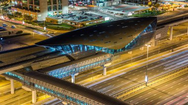 JLT bölgesi yakınlarındaki metro istasyonunda gece trafiği var. Dubai marina gökdelen çatısı havadan görünüyor.