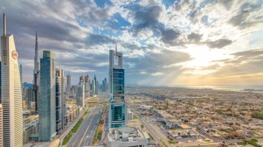 Dubai gökdelenleri, gün batımı akşam vakti. Dubai metro istasyonu ve Şeyh Zayed Yolu 'ndaki trafik. Kule çatısından gökyüzü görüntüsü. Güzel renkli bulutlu gökyüzü ve güneş ışığı