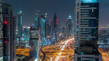 Dubai şehir mimarisi günden geceye geçiş zamanı. Şeyh Zayed yolu üzerindeki gökdelenler aydınlanmış ve kavşakta trafik var. Güzel bulutlu gökyüzü