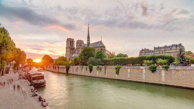 Paris, Fransa 'da Notre Dame de Paris katedralinin arkasında gün batımı. Başpiskoposluk köprüsünden görüntü. Tekne istasyonu ve rıhtım. Etkileyici gökyüzü ile Paris 'in mimarisi ve simgeleri.