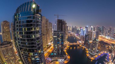 Dubai Marina gezinti güvertesi ve kanalı, gün batımından sonra Dubai, BAE 'de yüzen yat ve teknelerle panoramik hava manzaralı. Modern kuleler ve yoldaki trafik.