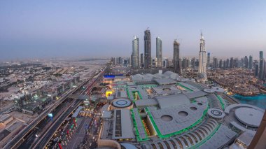 Dubai şehir merkezinden geceye geçiş zamanı modern ışıklandırılmış gökdelenler, alışveriş merkezleri ve yollardaki trafik. Gün batımından sonra yukarıdan panoramik görünüm