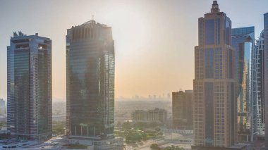 Jumeirah göl kulelerinin gündoğumunda gökdelenlerin havadan görünüşü cam yüzeyden yansıyan güneşle birlikte. Dubai marinasından çatı manzarası