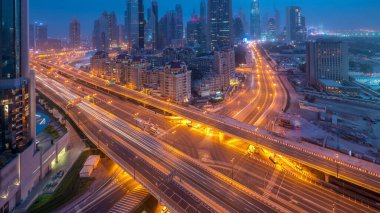 Dubai şehir merkezi, gece gündüz UAE karayolu trafiği ile hava değişimi. Al Saada caddesinin kavşağı ve finans merkezi yolu yakınında modern kuleleri olan gökdelenin çatısı manzaralı.