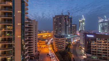 Gün batımından sonra Dubai Marina 'da gökdelenler ve hava yürüyüşü gününden geceye geçiş zamanı. Yol trafiği olan modern kuleler ve tekneler. Birleşik Arap Emirlikleri