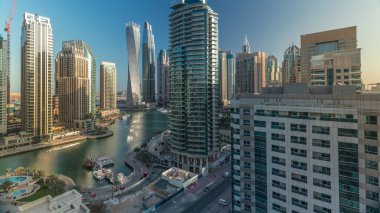 Dubai Marina yerleşim ve ofis gökdelenlerinin deniz manzarası. Gün doğumundan sonraki sabah gölgeler hızla hareket ediyor. Güneş camdan yansıyor. Yüzen tekneler ve yatlar