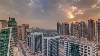 Dubai Marina ve Jlt 'deki çeşitli gökdelenlerin ve kulelerin gündoğumu görüntüsü. Şehir merkezindeki modern binaların gökyüzü bulutlu.