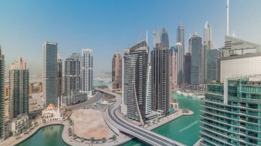 Dubai Marina yerleşim yeri ve ofis gökdelenlerinin deniz manzarası tüm gün boyunca gölgeler hızla ilerlerken. Yüzen tekneler ve yatlar. Cami ve köprü