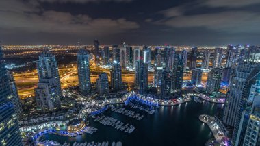 Dubai Marina, gökdelenleri ve Jumeirah göl kulelerini aydınlatmış ve Birleşik Arap Emirlikleri 'nde ışıklar kapanarak tüm gece boyunca yukarıdan panoramik bir manzara izlemiştir. Yolda trafik ve yüzen yatlar.