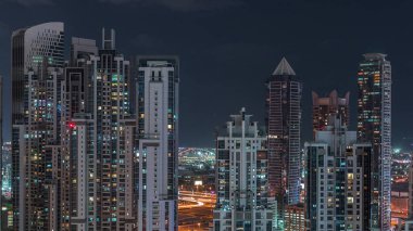 Business Bay, Dubai, Uae 'de birçok gökdelenle aydınlanmış konut ve ofis kompleksi. Pencerelerdeki ışıklar ve yollardaki trafik