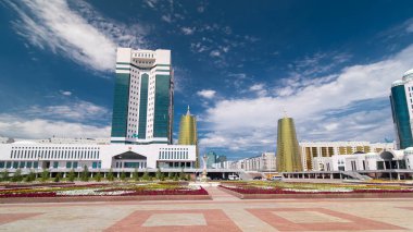 Nur-Sultan şehrinde Kazakistan Cumhuriyeti Senatosu 'nun inşa edilmesi. Ön planda çiçek açmış. Arka planda Nurzhol Bulvarı. Yazın mavi bulutlu gökyüzü