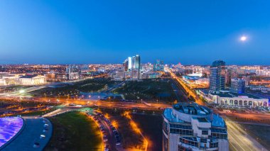 Şehir merkezi ve merkez iş bölgesi üzerindeki manzaranın günden geceye yükselmesi geçiş zamanı çatısı, Orta Asya, Kazakistan, Astana