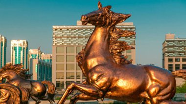 Atların heykelleri, Astana Opera Tiyatrosu 'nun önündeki yeşil çimlerde gün batımında, Kazakistan' da aşırı hızlanırlar. Nur-Sultan şehri