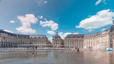 Place de la Bourse ve Miroir d 'eau hiperlapse Bordeaux, Fransa' da, tarihi mimariyi yansıtıyor. Turistler şehir simgesi ve çeşmenin tadını çıkarıyorlar. Trafik ve tramvay zamanı geçiyor..
