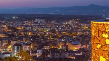 Nevsehir 'in tarihi şehir kentindeki eski şatonun hava görüntüsü. Günbekten geceye geçiş zamanı. Gün batımından sonra aydınlatılmış binalar ve yollar ile panoramik gökyüzü