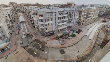 Beton yol yapımında çok sayıda işçi ve mikser makinesi, vinç, traktör zaman ayarlı çalışır. Tramvay raylarının yeniden inşası. Yukarıdan tüm gün boyunca gökyüzü görüntüsü