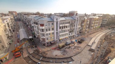 Şehir yolundaki tramvay rayları için koruyucu maske takviyesi olan işçiler yukarıdan havadan zaman ayarlı inşaat yapıyorlar. Vinç rayları boşaltıyor. Tramvay raylarının yeniden inşası.