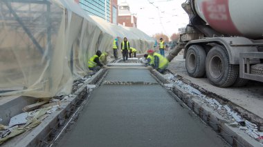 Çelik takviyesi yaptıktan sonra beton karıştırıcı zaman aşımına uğrayarak yolu hızlandırmak için hazır beton dökülüyor. Çadırla kaplı yeni raylar. Tramvay raylarının yeniden inşası
