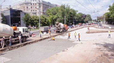Tramvay rayları onarımı ve bakım zamanı olan bir yol inşaatı. Beton karıştırıcı ve birçok işçiyle kavşağın ortasında çalışır..