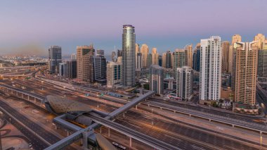 Dubai Yat Limanı gökdelenler hava üstten görünüm güneş doğmadan önce Jlt gelen Dubai gece gün timelapse, Birleşik Arap Emirlikleri için. Işıklı modern kuleleri ve Şeyh zayed yolu üzerinde trafik.