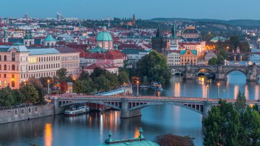 Prag 'daki Vltava Nehri' nin hava akşam manzarası ve trafik ile aydınlanan köprüler. Kuleler ve kuleler. Tekneler ve gemi suda yüzüyor. Hanavsky köşkünden üst görünüm
