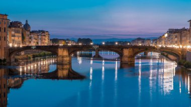 Ponte Santa Trinita 'nın (Kutsal Üçlü Köprü) alacakaranlık sahnesi gün batımından sonra suya yansıyarak Arno Nehri üzerinde geçiş zamanı. Floransa, Toskana, İtalya