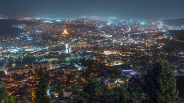 Alacakaranlıkta Tiflis şehri, Gürcistan 'dan gece geçiş zamanı. Şehir merkezinin ve Tiflis 'teki Kura Nehri' nin üst manzarası. Gün batımından sonra Gürcistan başkentinin havadan görünüşü