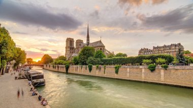 Paris, Fransa 'da Notre Dame de Paris katedralinin arkasında gün batımı. Başpiskoposluk köprüsünden görüntü. Tekne istasyonu ve rıhtım. Etkileyici gökyüzü ile Paris 'in mimarisi ve simgeleri.