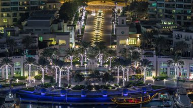 Dubai Marina şelalesi havadan geceye geçiş zamanı, lüks yatları ve marina gezinti güvertesi olan liman, Dubai, Birleşik Arap Emirlikleri. Aydınlatılmış avuçlar ve yol trafiği