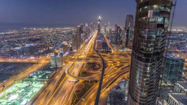 Dubai şehir merkezindeki ufuk çizgisi günden geceye geçiş zamanı. Şeyh Zayed kavşağındaki çok sayıda aydınlatma kulesiyle çatıdaki trafiğin görüntüsü.