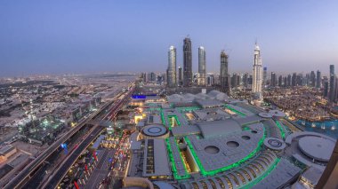 Dubai şehir merkezinden geceye geçiş zamanı modern ışıklandırılmış gökdelenler, alışveriş merkezleri ve yollardaki trafik. Gün batımından sonra yukarıdan panoramik görünüm